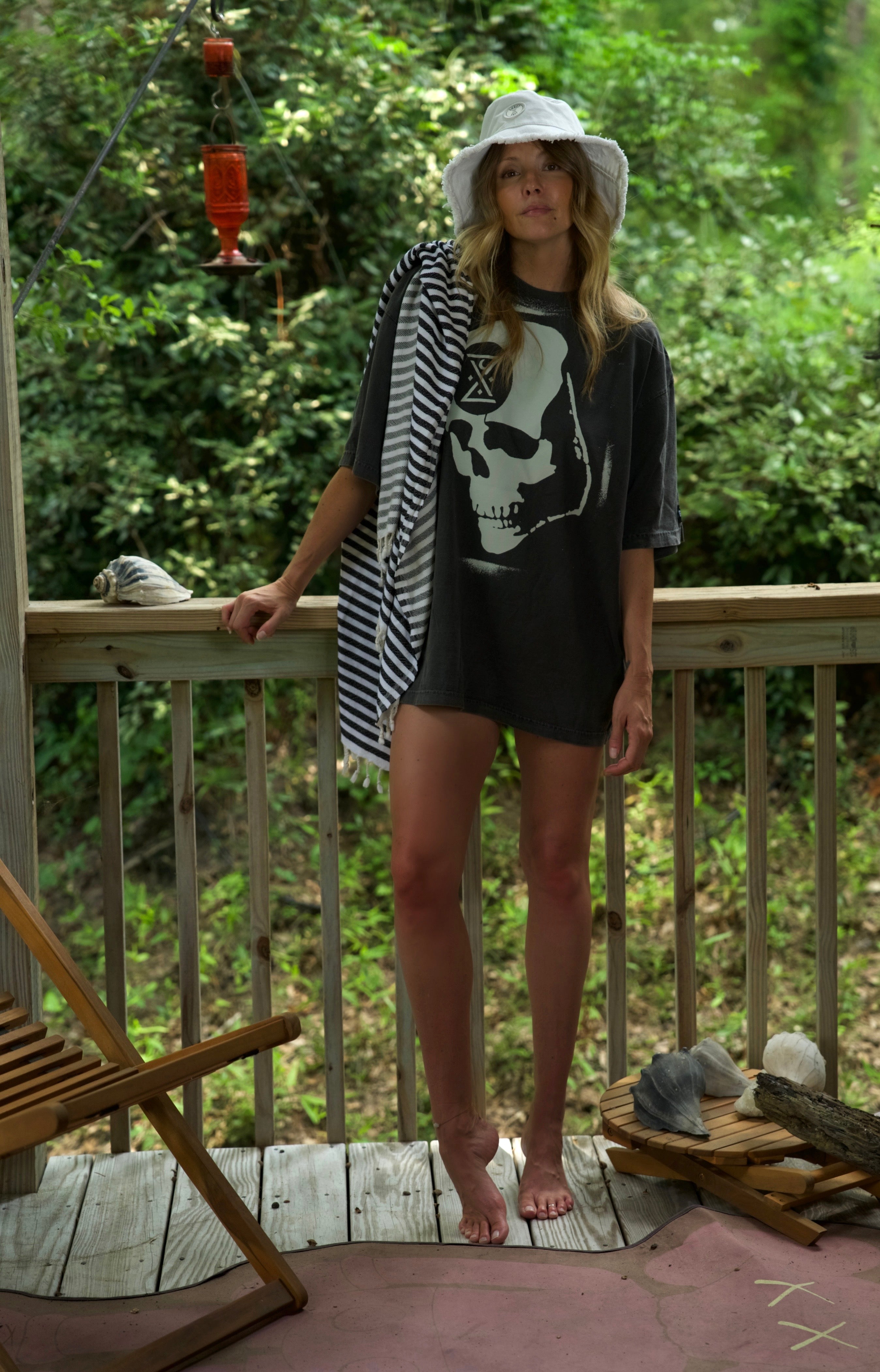 woman leaning against wooden railing in a ghost ship ominous skull t-shirt